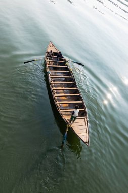 Hindistan 'daki bir grup çocuk tarafından yeşil suda kürek çekilen ahşap bir teknenin üst görüntüsü.