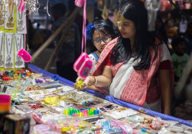 Birbhum, Batı Bengal, Hindistan - 26 Şubat 2024: Bir kadın ve bir kız geceleyin kırsal bir panayırdan alışveriş yapıyorlar