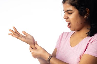 Eklem ağrısı için bileğini tutan Hintli bir kadın beyaz arka planda acı dolu bir ifade gösteriyor.