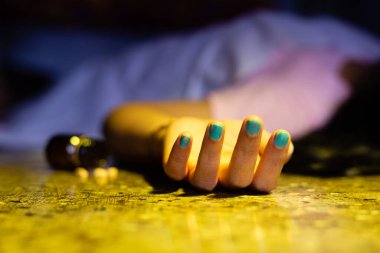 Bir Hintli ya da Asyalı kadın cesedi uzanmış elleri ve uyku hapları karanlık bir odada intihar konseptiyle yerde yatıyor.