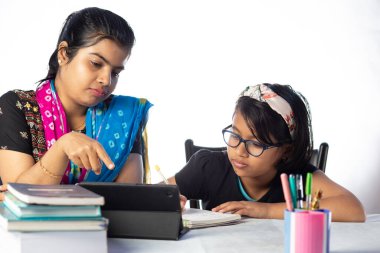 Hintli bir kız öğrenci annesinin yanında tabletle çalışıyor, öğretmen: özel öğretmen konsepti