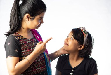 Hintli bir anne beyaz arka planda kızının kulağını çekip azarlıyor.