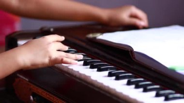 Önünde açık bir kitapla Hint klasik müzik enstrümanı harmonyumu çalan bir eli kapat