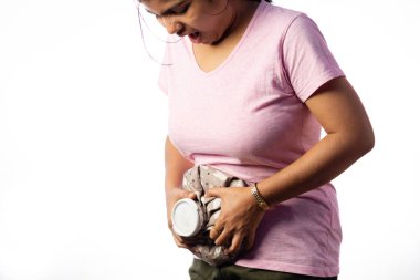 An Indian woman applying hot water bag on her belly for pain relief on white background clipart