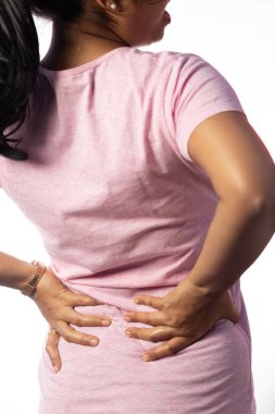 An Indian unrecognizable woman holding her back for pain showing painful expression on white background clipart