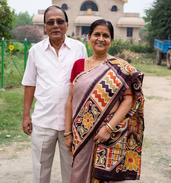 Açık havada gülümseyen yaşlı bir Hintli çiftin portresi.