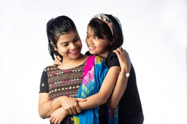 Hintli anne ve çocuk kucaklaşıyorlar. Beyaz arka planda gülümseyerek sarılıyorlar.