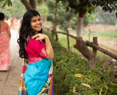 Geleneksel Hintli güzel bir Bengalli kadın sari giyip açık havada gülümsüyor.