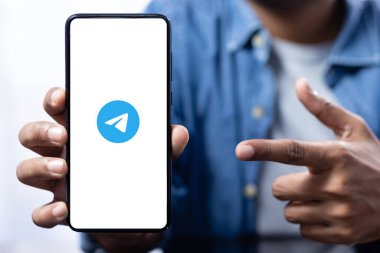 Hintli bir erkeğin işaret ettiği telgraf logosuyla akıllı bir telefon ekranını kapat