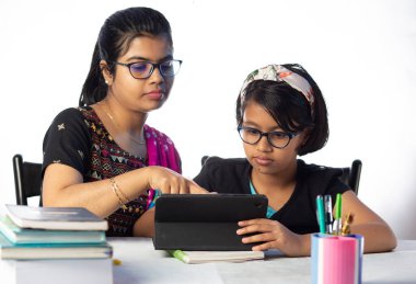 Hintli bir kız öğrenci annesinin yanında tabletle çalışıyor, öğretmen: özel öğretmen konsepti