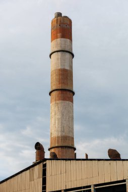 Bulutlu gökyüzünde arka planda emniyet valfleri ve bacası olan termik santral kazanı manzarası