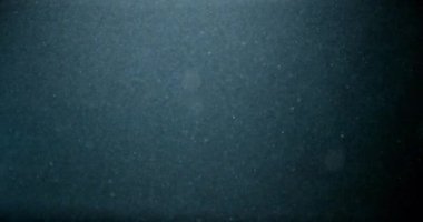 Küçük toz parçacıkları mavi arka planda suyun altında yavaş çekimde yüzerler..