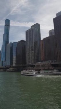 Chicago, Illinois, ABD, 15 Nisan 2024. Chicago 'da Riverwalk' ta çekilen dikey bir film klibi. Tekneyle seyahat eden turistler var..
