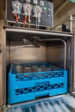 Açık bulaşık makinesi kapısının iç tarafı manzaralı, raflar ve bulaşıklar da dahil. Resim makinenin içindeki organize düzeni vurgular.