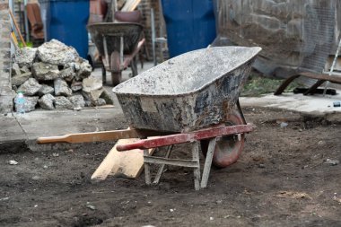 Yıpranmış bir el arabası, enkaz ve kaya yığınlarıyla dolu yoğun bir inşaat sahasında ağır iş ve sanayi taşımaktadır..