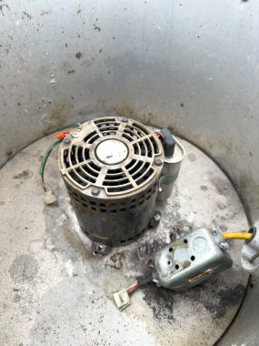 Kullanımı mekanik ayarlar, bakım senaryoları veya montaj bağlamlarında vurgulanan, görünür kablolama ve konnektörlerle yıpranmış bileşenleri gösteren endüstriyel fan motorunun ayrıntılı görüntüsü.