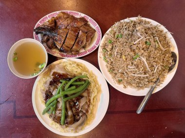 Çin mutfak zımbaları içeren nefis bir yemek, kızarmış ördek, yumurtalı erişte, kızarmış pirinç ve çorba, ahşap bir masada güzelce düzenlenmiştir..