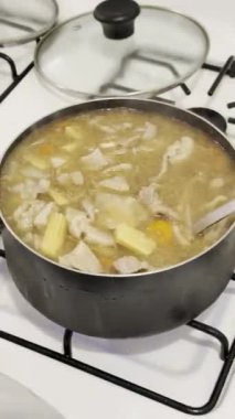 Fırının üstündeki tencerede çorba yapmak ve kepçelemek Tayland çorbası için karışık sebze ve domuz eti..