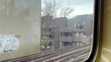 Şikago, ABD, Jan, 31,2024, bir metro treni rayları boyunca ilerliyor, grafitiyle kaplı bir duvarı gösteriyor. Bulutlu gökyüzü, şehir hayatına kasvetli bir atmosfer ekliyor..