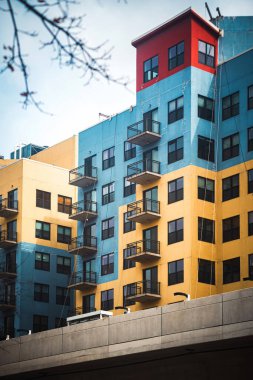 Küçük balkonlarla tamamlanmış, zıt mavi ve sarı duvarlara sahip canlı bir renk şemasına sahip modern bir şehir apartmanı. Chicago 'daki dinamik ve yapısal unsurlar mimari stili ve kültürel canlılığı vurgular..