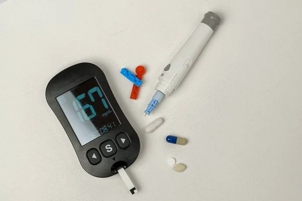 Diabetes treatment kit with digital blood glucose meter, lancets, lancing device on white background