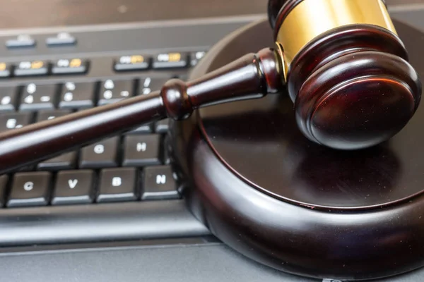 stock image A judge presides over a court, brandishing the mace of justice while a laptop and keyboard display evidence in an ongoing cybercrime case. Technology aids communication between legal professionals.