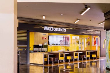 Barselona, İspanya - 19 Mart 2023. McDonald 's Corporation, 1940 yılında Amerika Birleşik Devletleri' nde kurulan çok uluslu bir fast food satış mağaza zinciri. İçerideki masalar