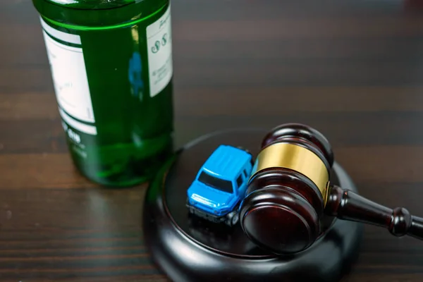 Judge\'s mace on a table in a court of law, glass of whiskey and miniature car. No drinking while driving concept
