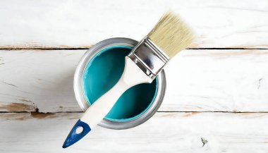 Mavi bir boya kutusu içinde boya fırçası olan ahşap bir masada oturur. Mavi boya resim için kullanılmaya hazır.