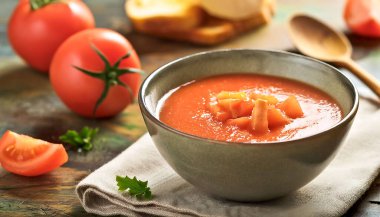 Bir kase geleneksel İspanyol gazpacho otlarla süslenmiş, ahşap bir masada kırsal bir kasede servis ediliyor..