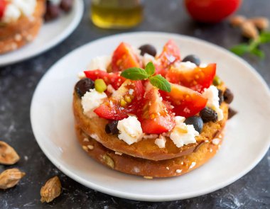 Dakos taze, iştah açıcı bruschetta olgun domatesler, feta peyniri, zeytin ve fesleğen, kırsal bir masaya konur.