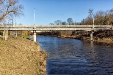 In winter, an old pedestrian bridge over the river in the city park area