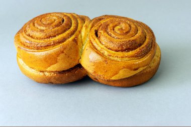 Tarçınlı iki rulo çörek ve gri arka planda şeker kaplı salyangoz manzarası