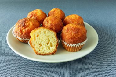 Mini kekler, gri bir masa örtüsünün üzerindeki bir tabakta çörekler.