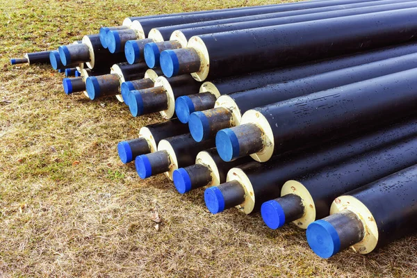 A pile of water pipes with thermal insulation isotherm, in a meadow during spring