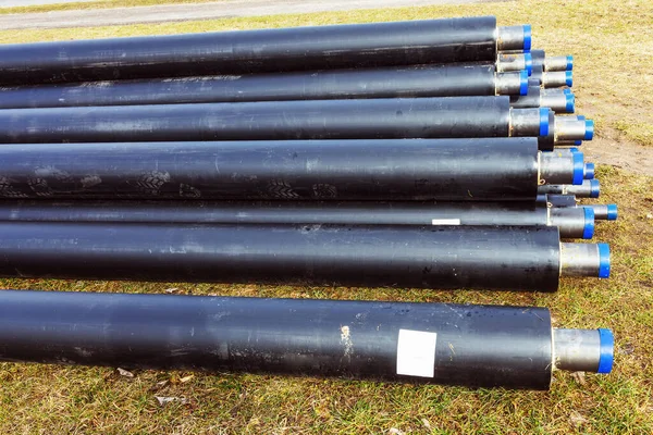 Pile of water pipes with thermal insulation isotherm, side view in meadow during spring