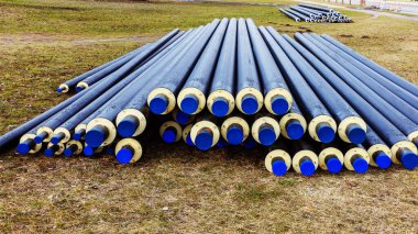 Isı yalıtım izolasyonlu iki yığın su borusu, ilkbaharda bir çayırda.