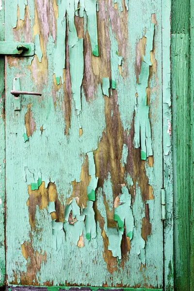 Peeling green paint on a wooden door with crack and peeling patterns