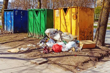 Şehirde, üç farklı katlanabilir konteynırın yanında çeşitli çöp yığınları var.