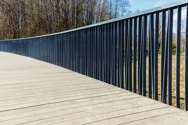 Stock image A view of the pedestrian wooden bridge with metal railings in the spring