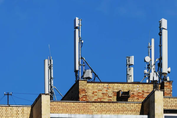 蓝色天空背景下的砖头住宅大楼上的各种通信天线 — 图库照片