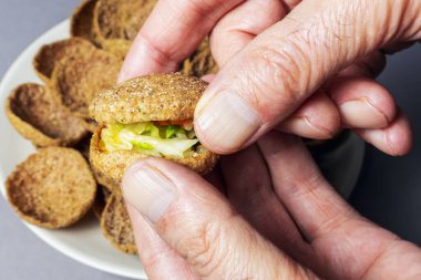 Bir ısırık çavdar ekmeği, sarımsaklı tost ve bulanık arka planda elleri dolduran sebze.