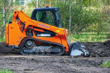 Lastik izleri olan mini Cramo doldurucu, parkta zemini dümdüz eden bir buldozer. Panevezy 'ler. Litvanya. - 28. 04 numara. 2023.