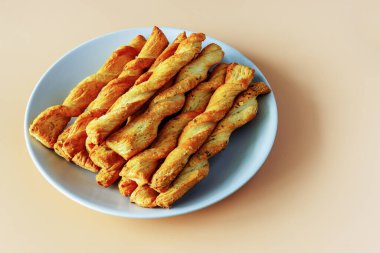 Turuncu bir arka planda bir tabakta rulo tereyağlı maya hamuru.