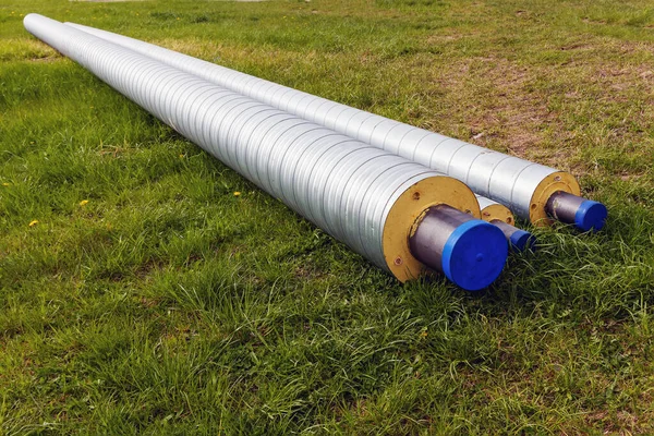 In the spring, water pipes with thermal insulation in the meadow on a sunny day, close up