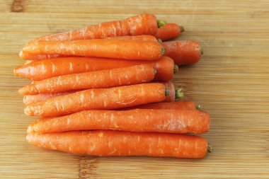 Bambu kesme tahtasında yıkanmış taze ve çıtır çıtır havuç yığını.