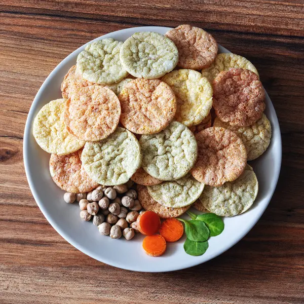 低脂肪のひよこ豆のチップの健康的なビーガンスナック松の木のテーブルの表面上のプレートに野菜と — ストック写真