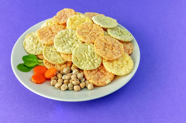低脂肪のひよこ豆のチップの健康的なビーガンスナック紫色の背景にプレート上の野菜と — ストック写真
