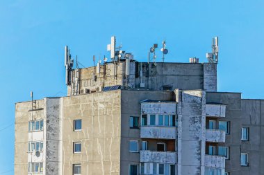 Mavi gökyüzü arka planındaki bloktaki yerleşim yerlerinde çeşitli iletişim antenleri