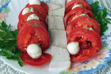 Domatesli domuz pastırması ve masa örtüsündeki mozzarella peynirinin üst görüntüsü.